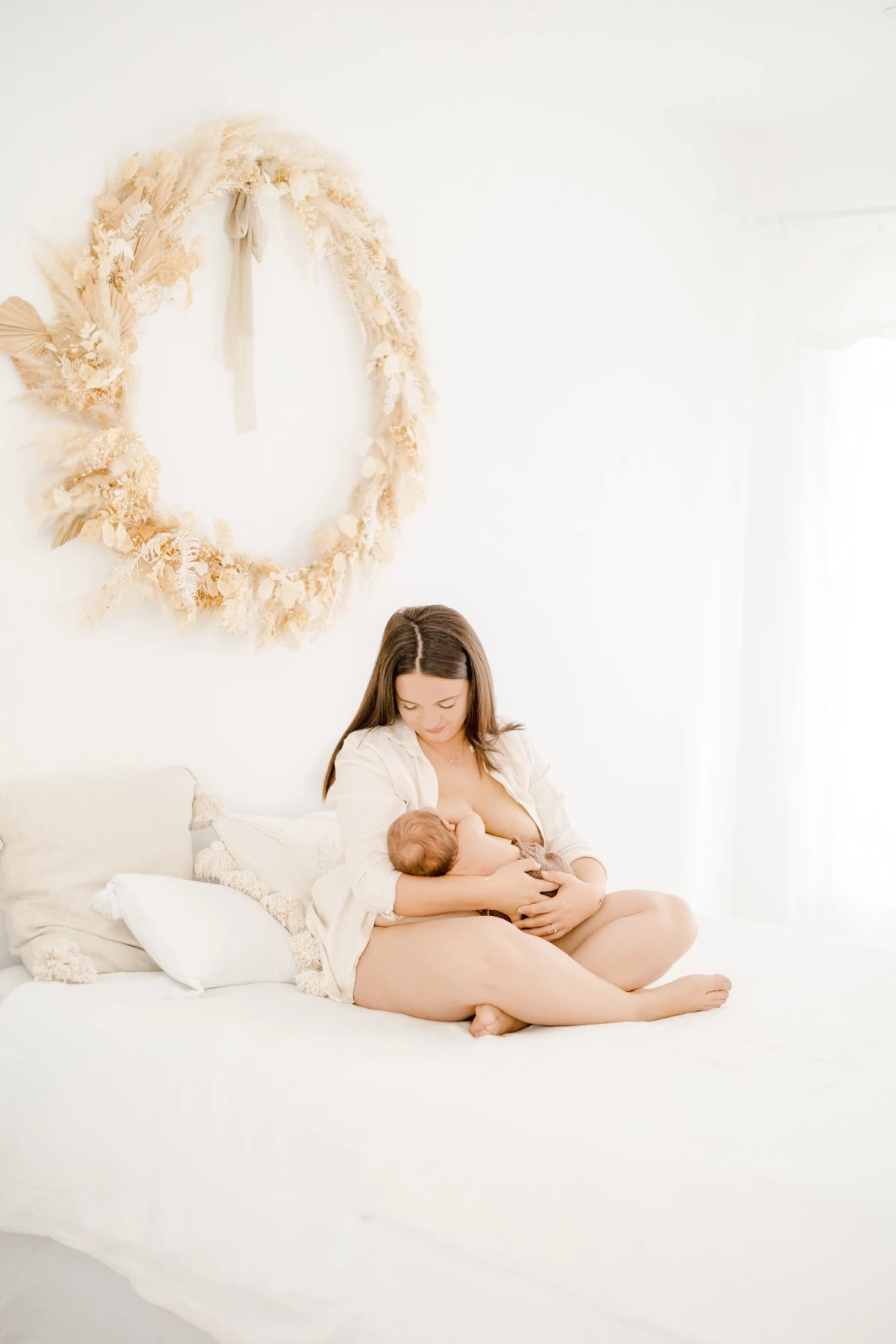 Séance allaitement au studio : jeune maman nourrit son nouveau-né dans une ambiance de douceur et d'intimité, lumière naturelle