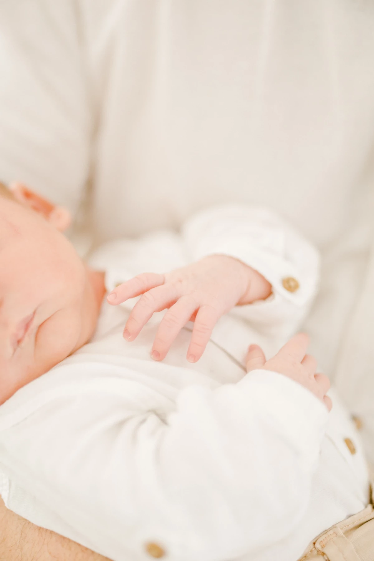Séance nouveau-né au studio : mains de bébé délicatement posées, atmosphère de douceur et tendresse dans une lumière douce