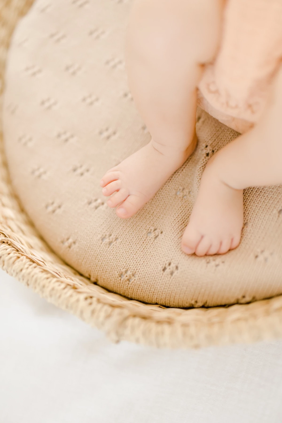 Séance naissance en studio : pieds de bébé de 4 mois posés sur un coussin beige, atmosphère douce et lumineuse