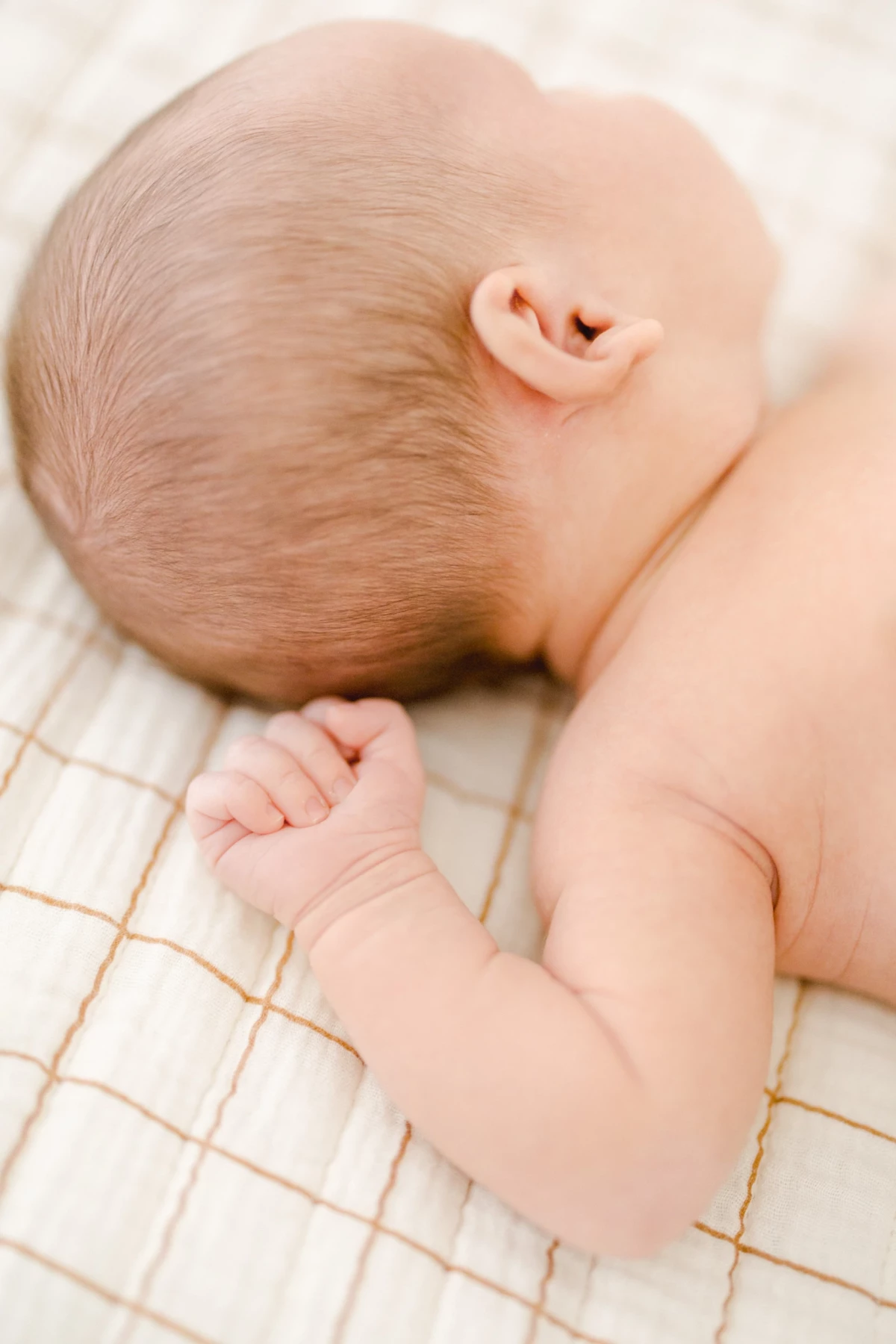 Séance nouveau-né au studio : bébé endormi paisiblement sur un matelas beige, dans une ambiance de douceur et de sérénité