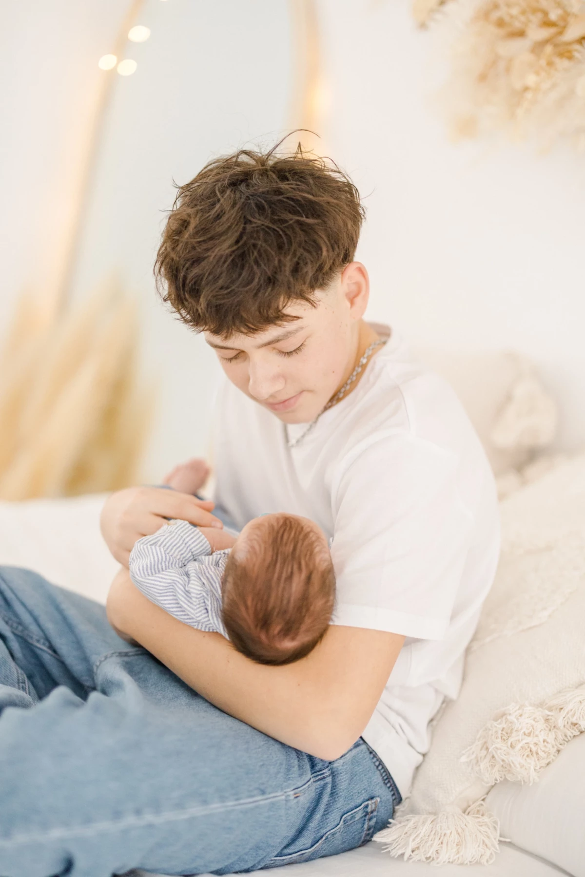 Séance naissance au studio : grand frère enlace tendrement son nouveau-né dans une lumière douce et naturelle, instant précieux