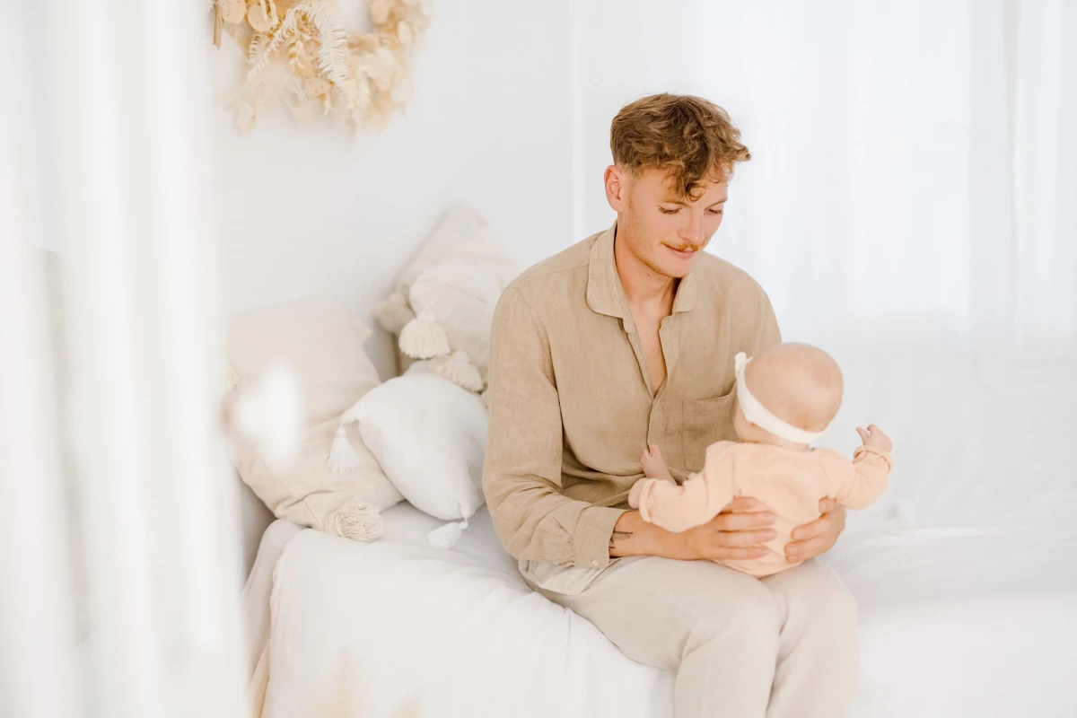 Séance naissance en studio : maman allaite son bébé de 4 mois dans une ambiance beige et blanche, lumière douce et naturelle