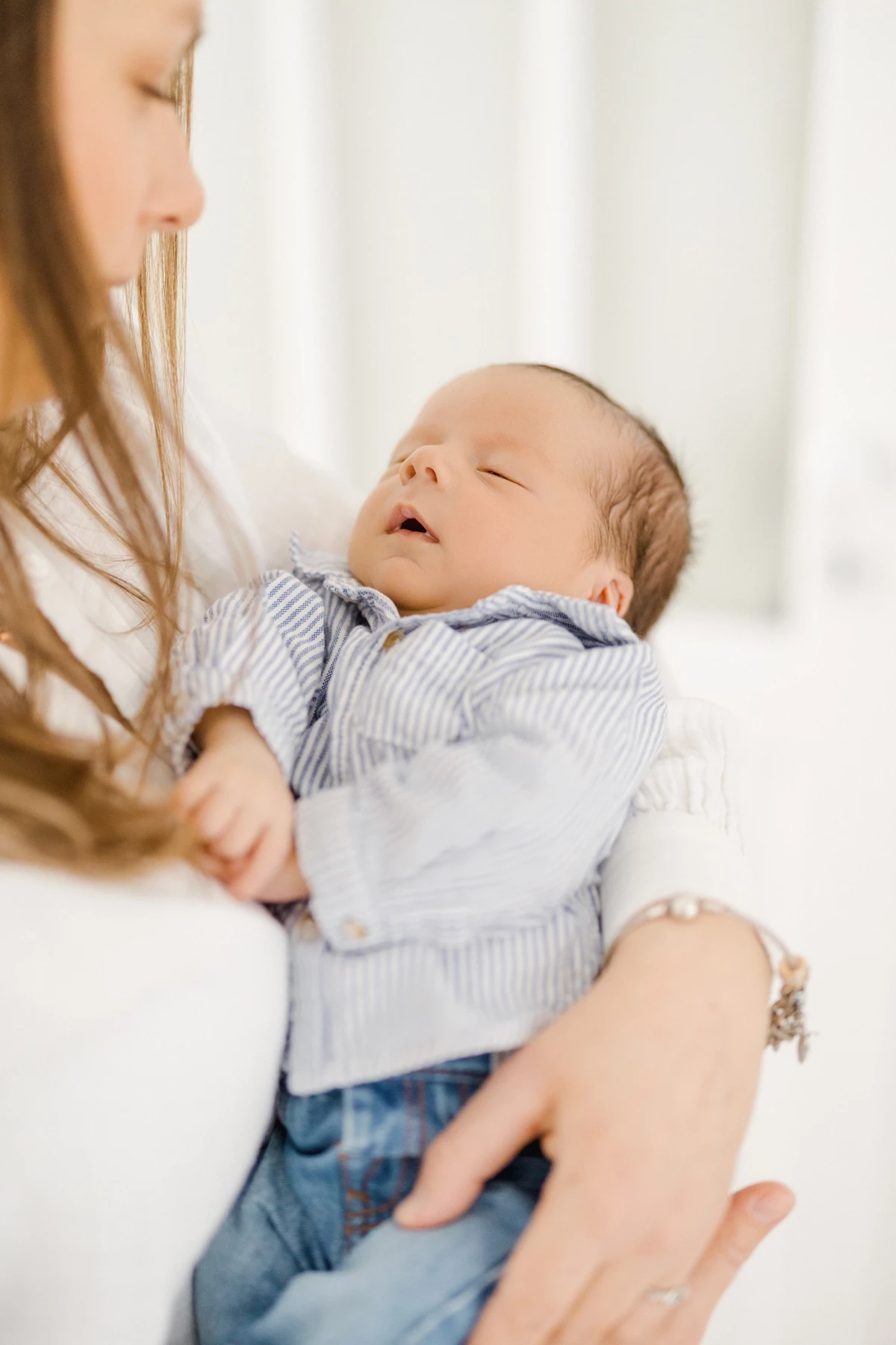 Séance naissance au studio : maman tient son nouveau-né dans ses bras, bébé apaisé dans une ambiance de tendresse infinie