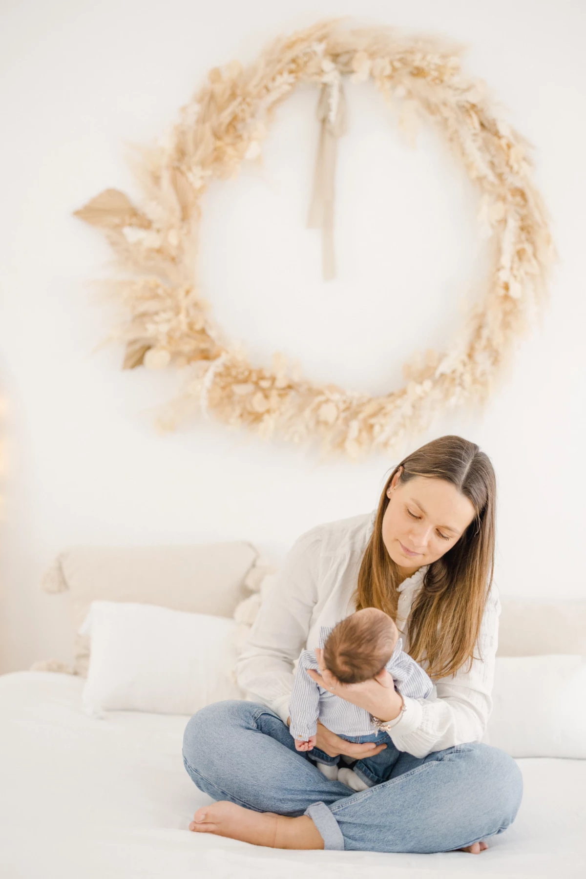 Séance naissance en studio : maman allaite son nouveau-né dans une ambiance douce et intimiste, lumière naturelle blanche