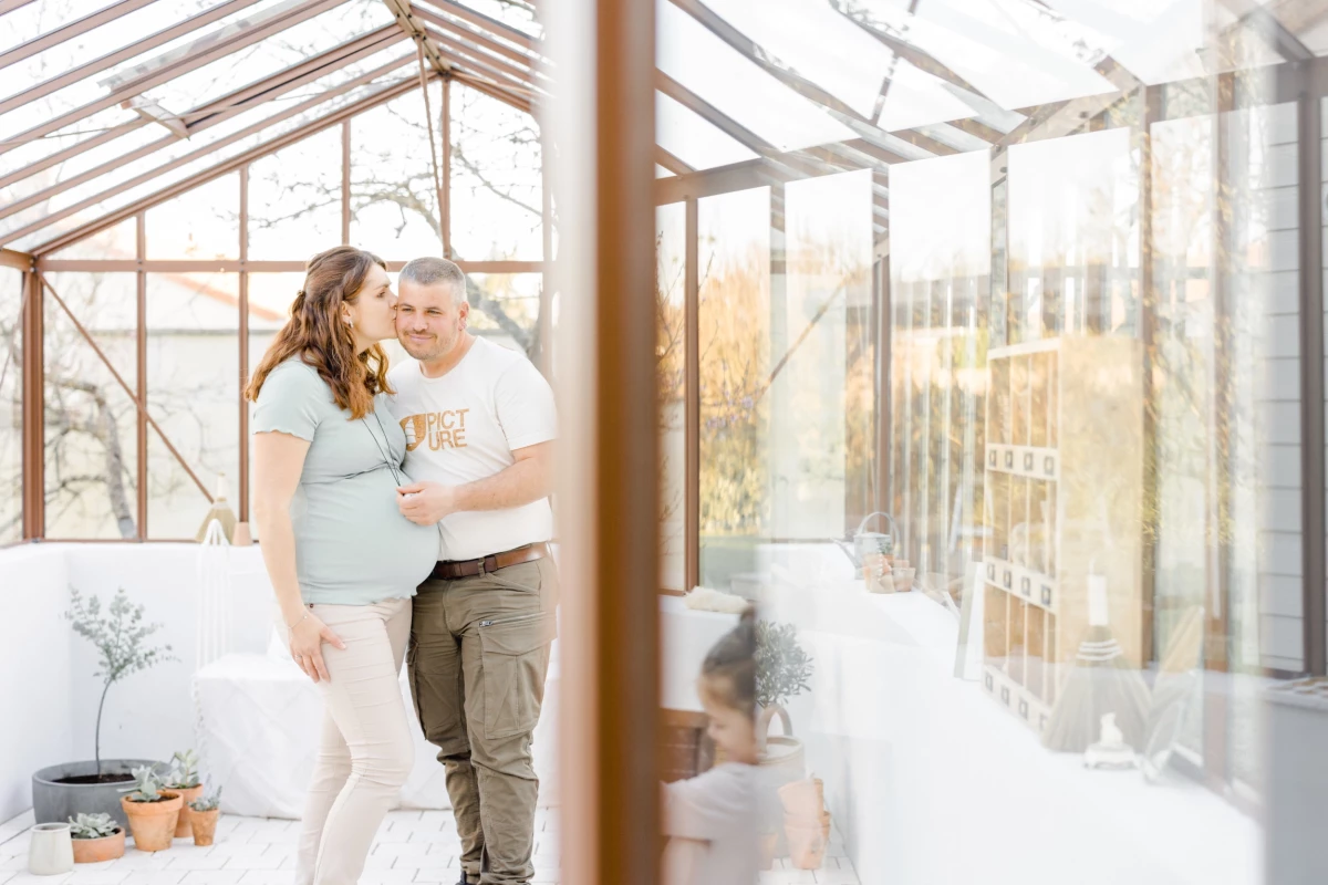 Séance grossesse en studio : future maman et son enfant partagent un moment de tendresse dans une verrière lumineuse