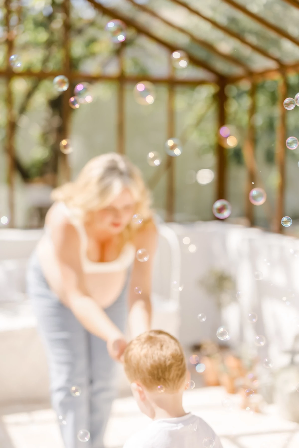 Séance famille au studio : maman et son enfant partagent un moment de complicité ludique entourés de bulles de savon
