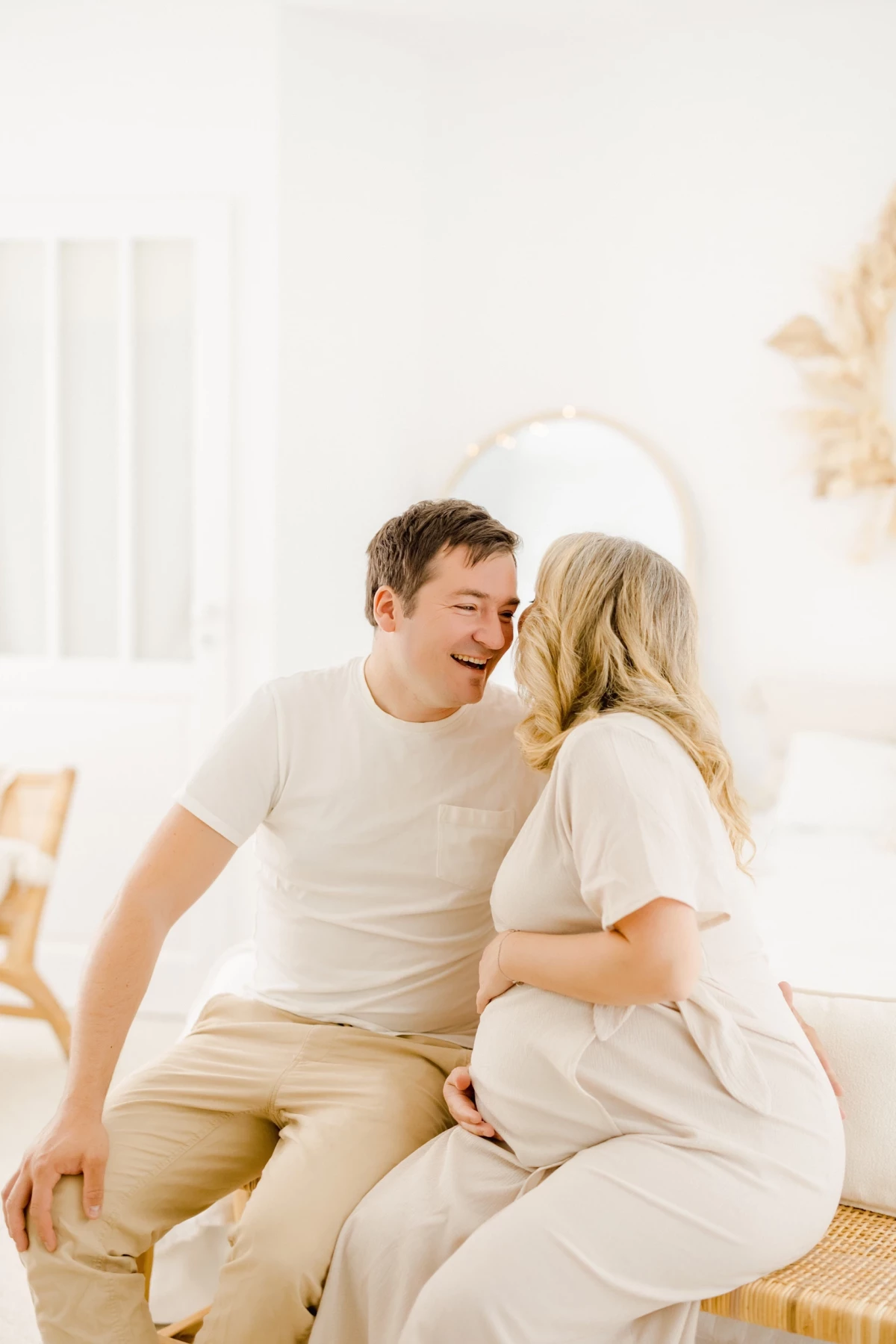 Séance grossesse au studio : couple complice partage un moment de tendresse dans une ambiance douce et lumineuse aux tons beige