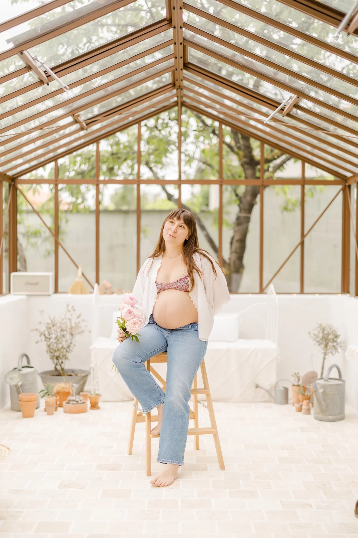 Séance grossesse en verrière : future maman pose assise dans une ambiance bucolique baignée de lumière douce et naturelle