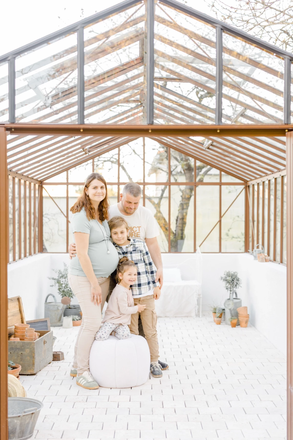 Séance grossesse en famille dans une verrière lumineuse : parents et enfants réunis dans une ambiance intime et chaleureuse