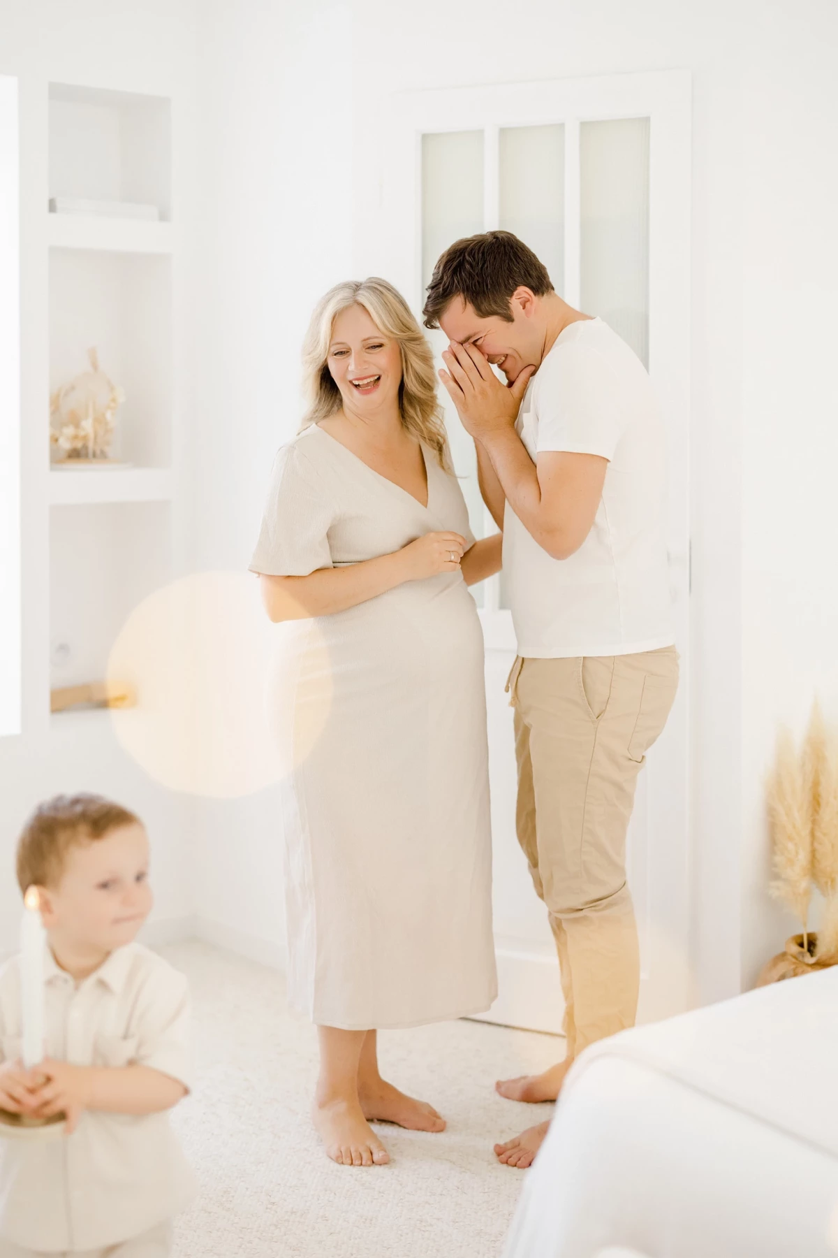 Séance grossesse au studio : couple complice partage une surprise émouvante avec leur fils, ambiance douce et lumineuse