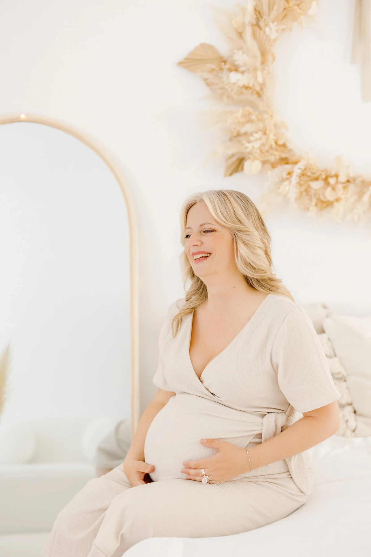 Séance grossesse au studio : future maman souriante caresse son ventre rond dans une ambiance douce et lumineuse