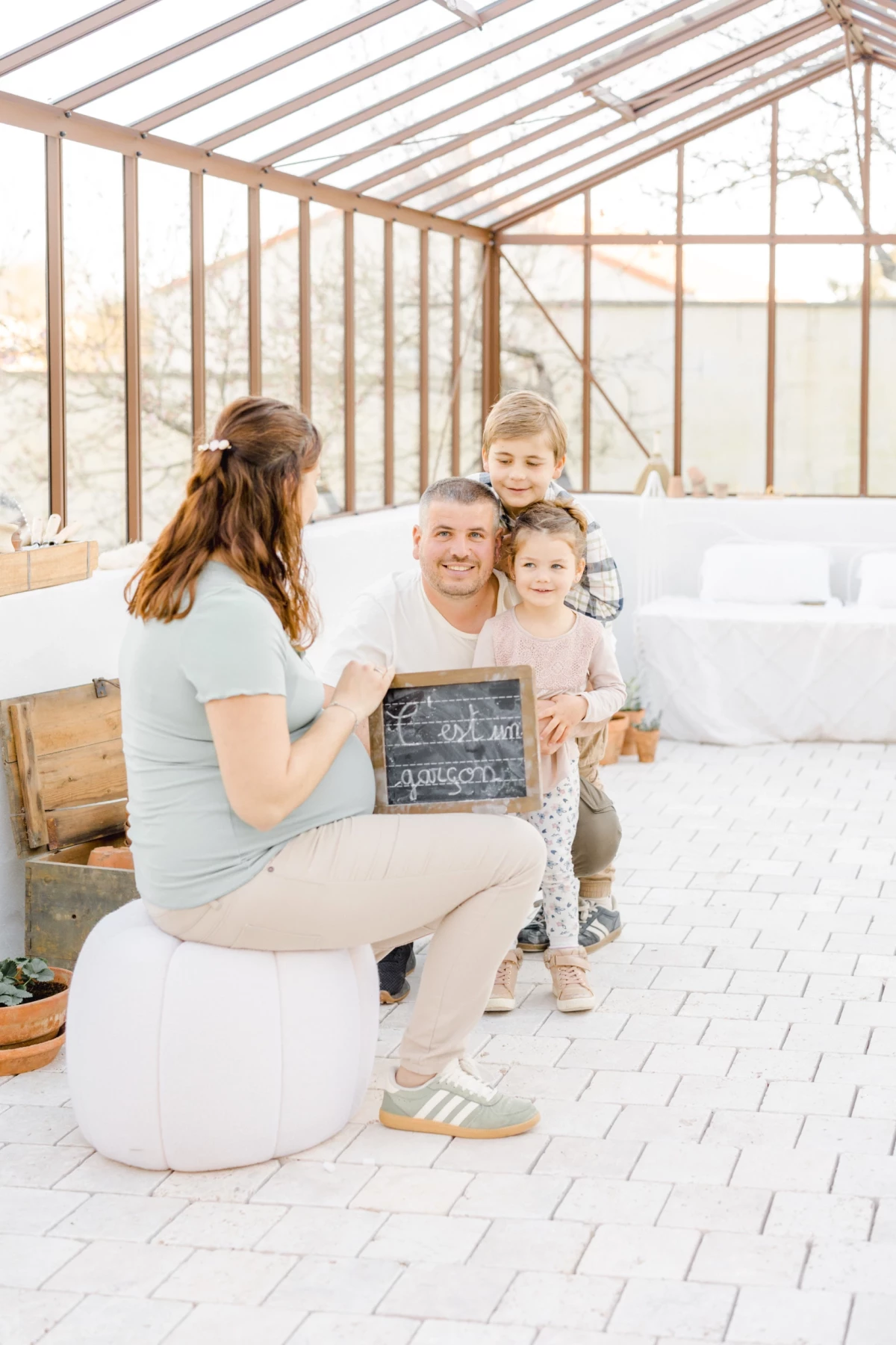 Séance grossesse famille en Vendée : parents et enfants réunis dans une verrière lumineuse, partageant complicité et tendresse