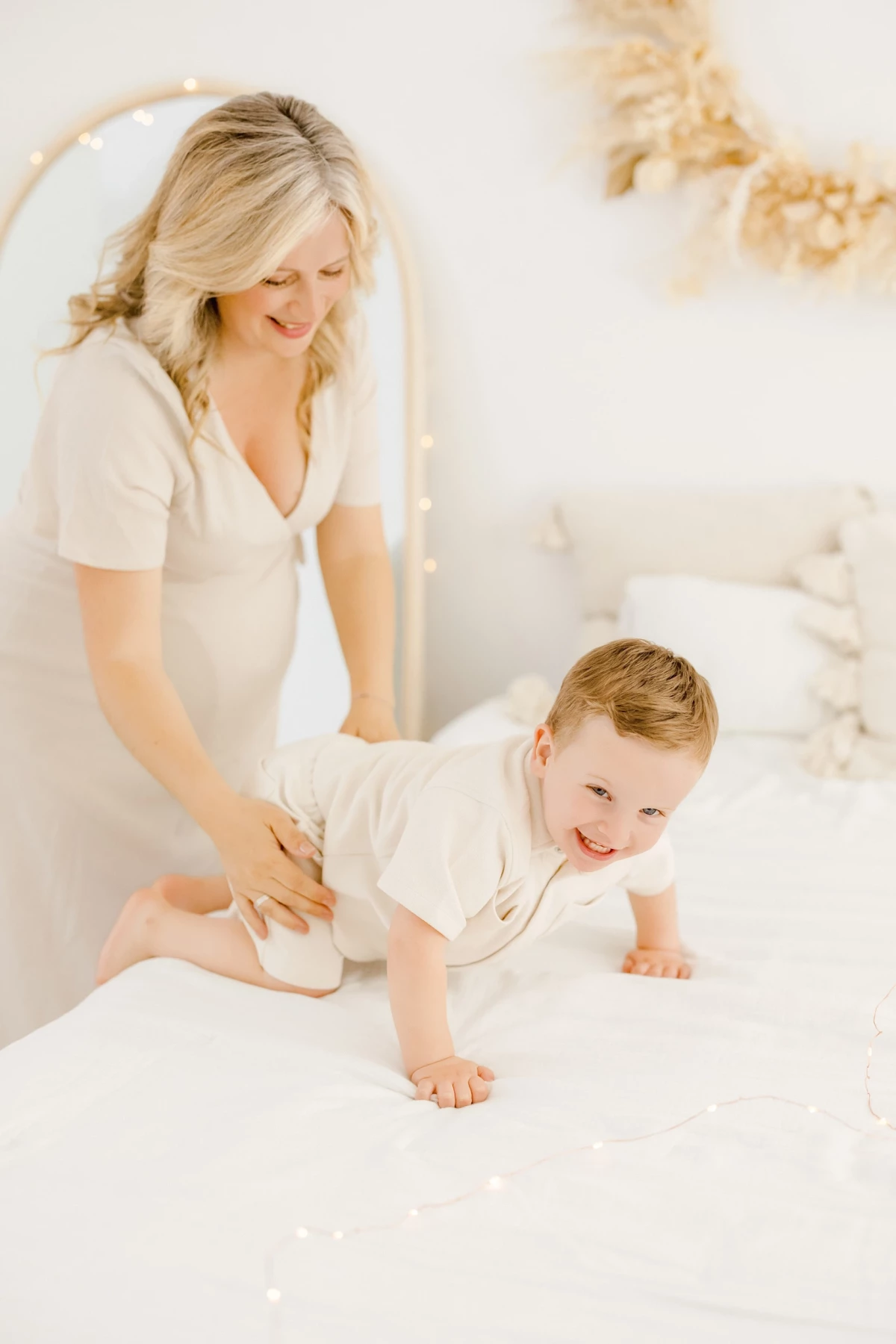 Séance famille en studio : maman accompagne son petit garçon souriant dans un moment de complicité tendre et lumineuse