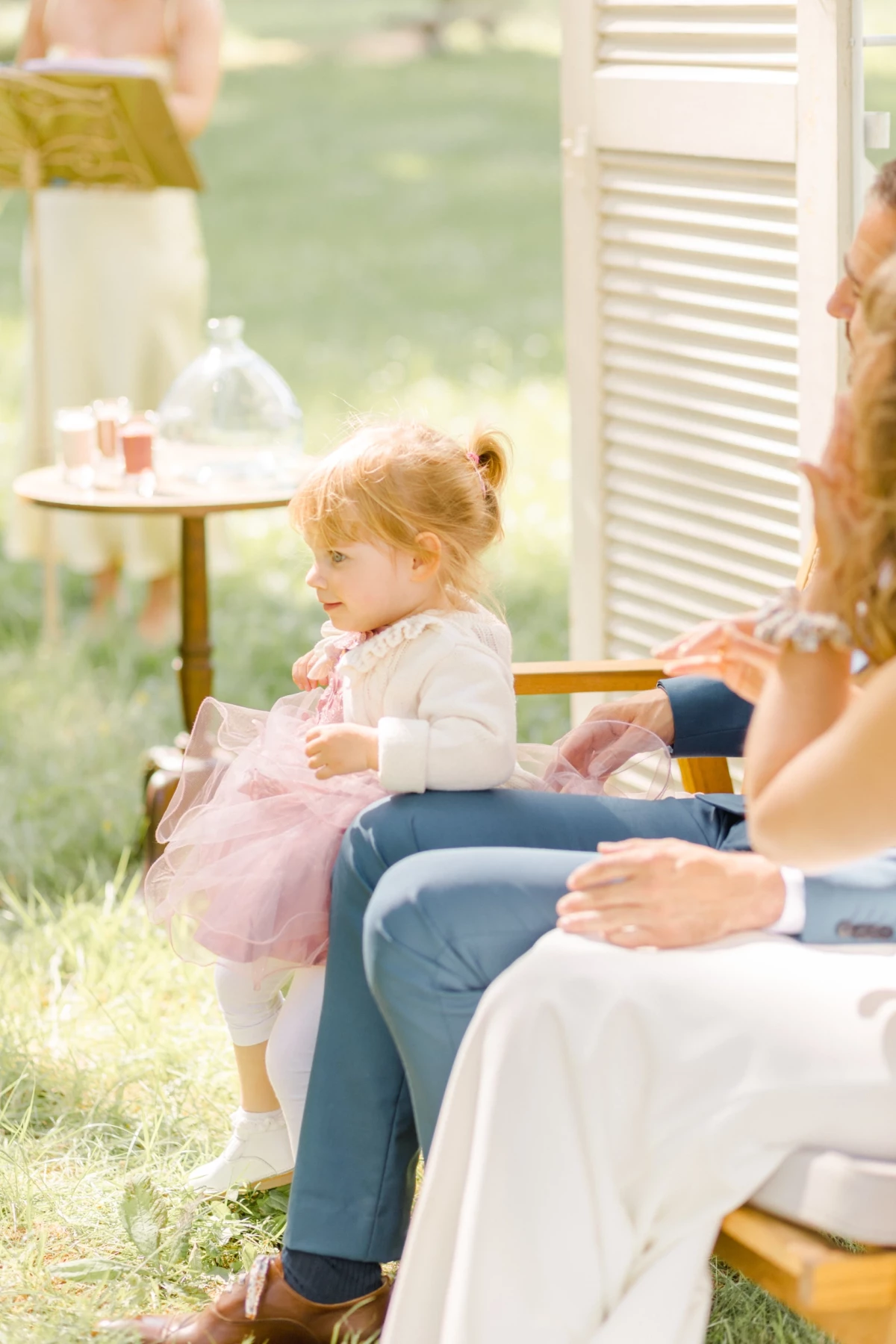 Petite fille en robe rose tutu assise sur une chaise lors d'une cérémonie en plein air
