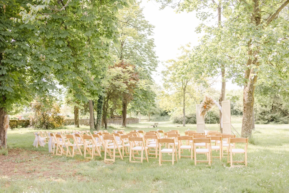 Cérémonie de mariage en plein air avec rangées de chaises blanches disposées sous les arbres verdoyants