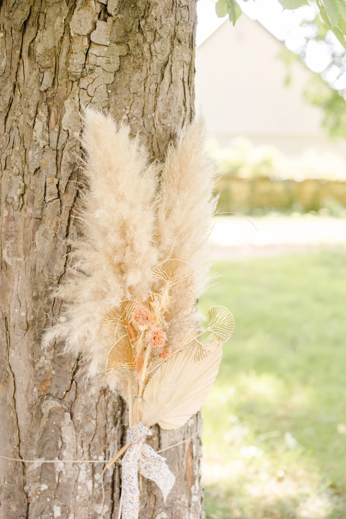 Bouquet de fleurs séchées et pampas attaché contre un tronc d'arbre pour une décoration de mariage bohème