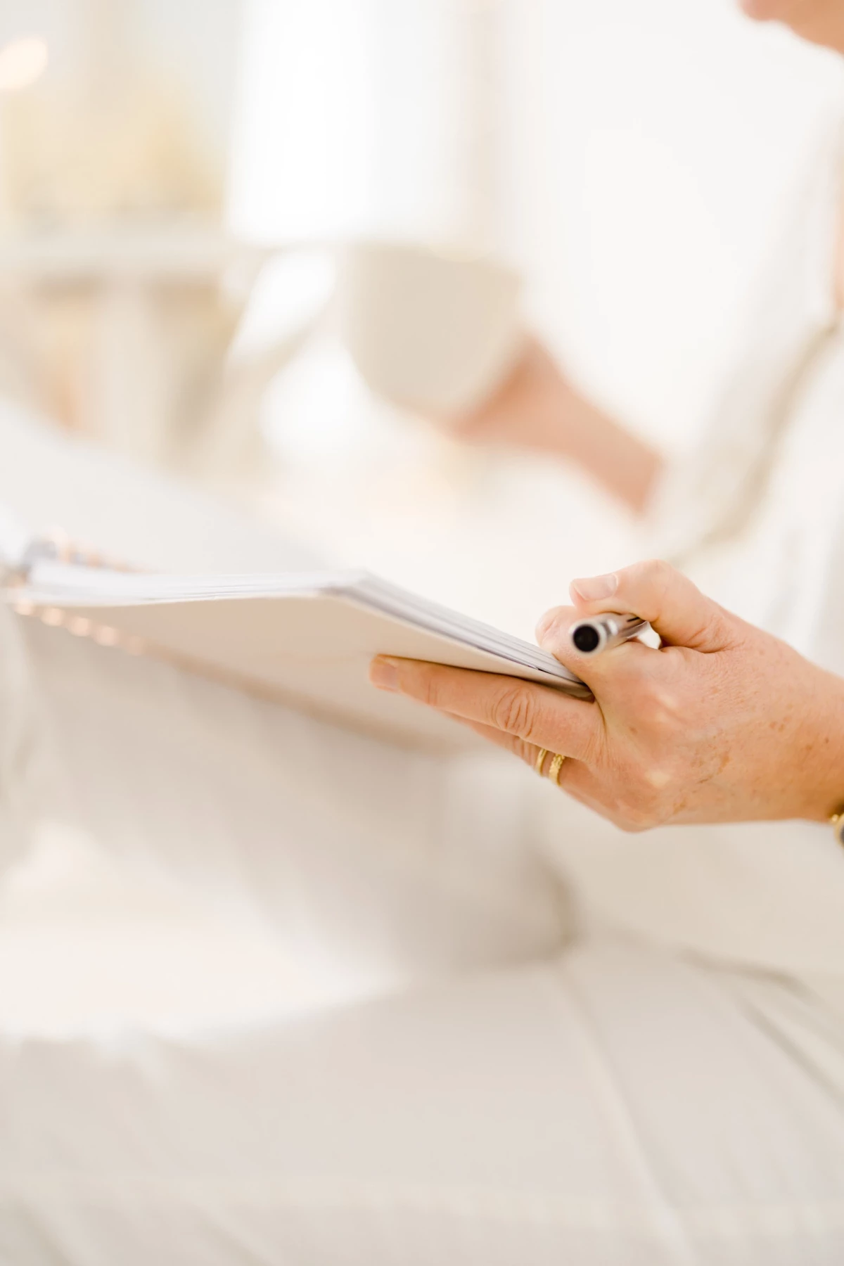 Professionnelle en tenue blanche tenant délicatement un carnet, dans une lumière douce