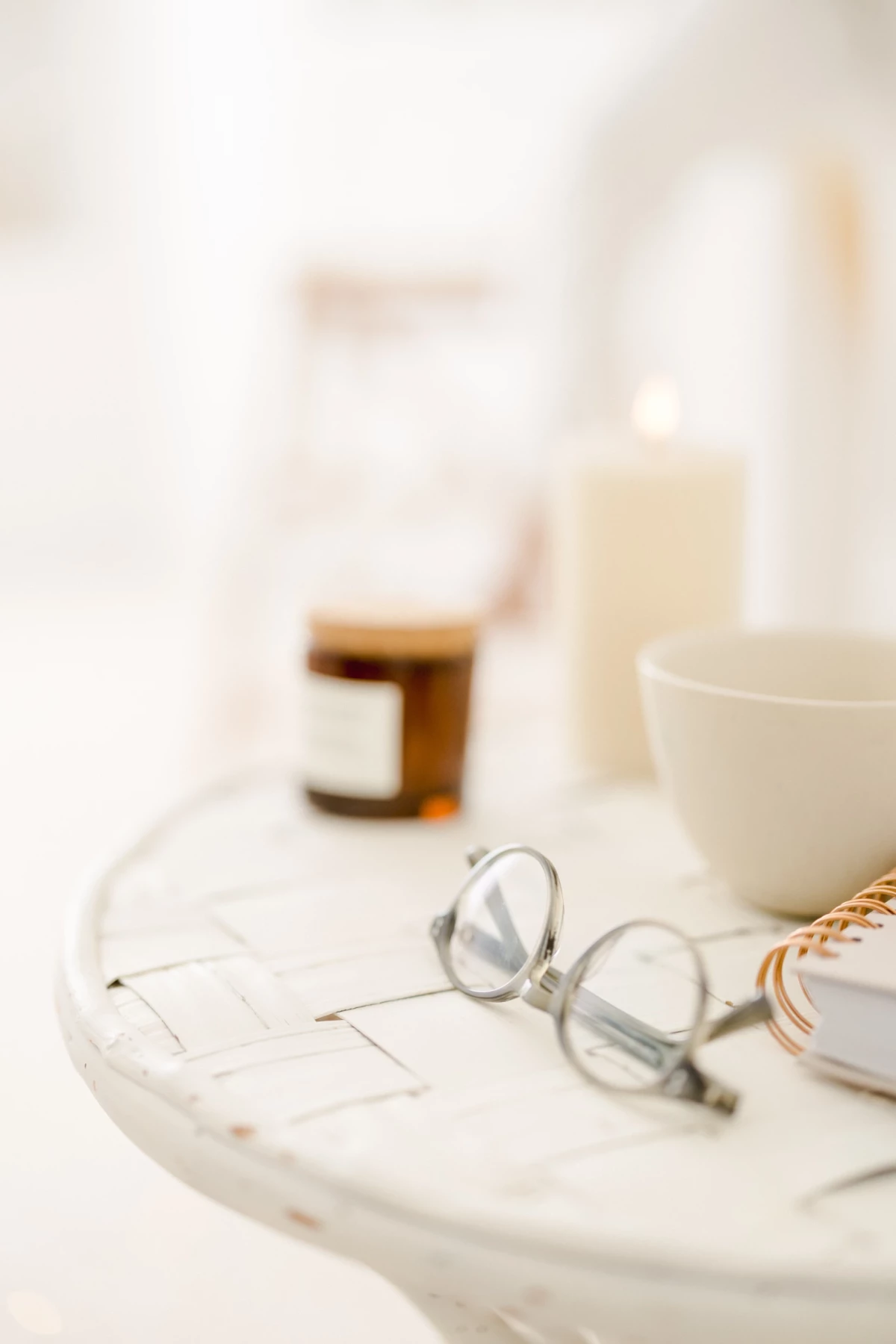 Lunettes délicatement posées sur un plateau de marbre blanc entouré de bougies et accessoires raffinés