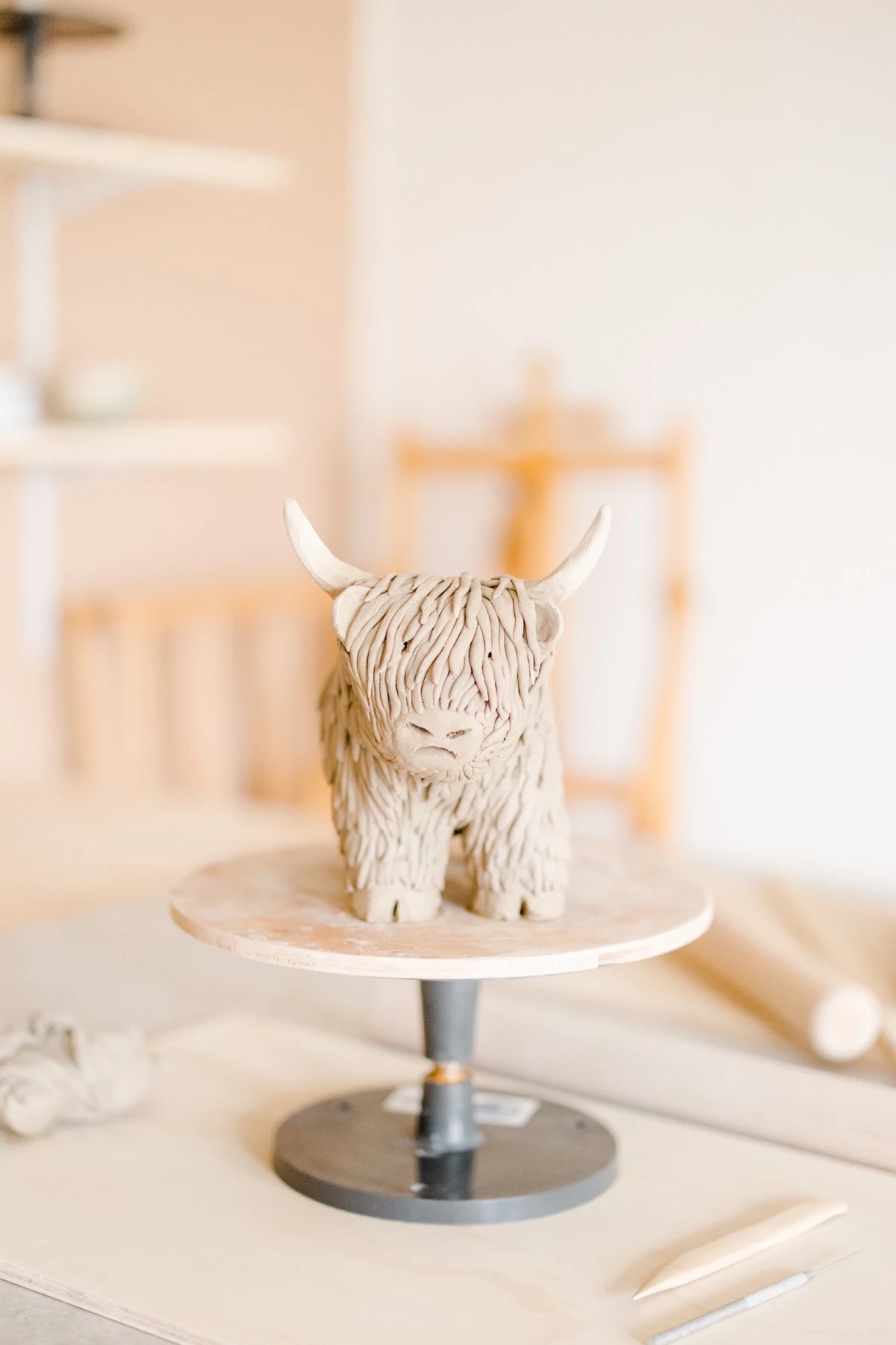 Portrait corporate dans un atelier céramiste : sculpture artisanale d'un yak en céramique blanche sur un présentoir design