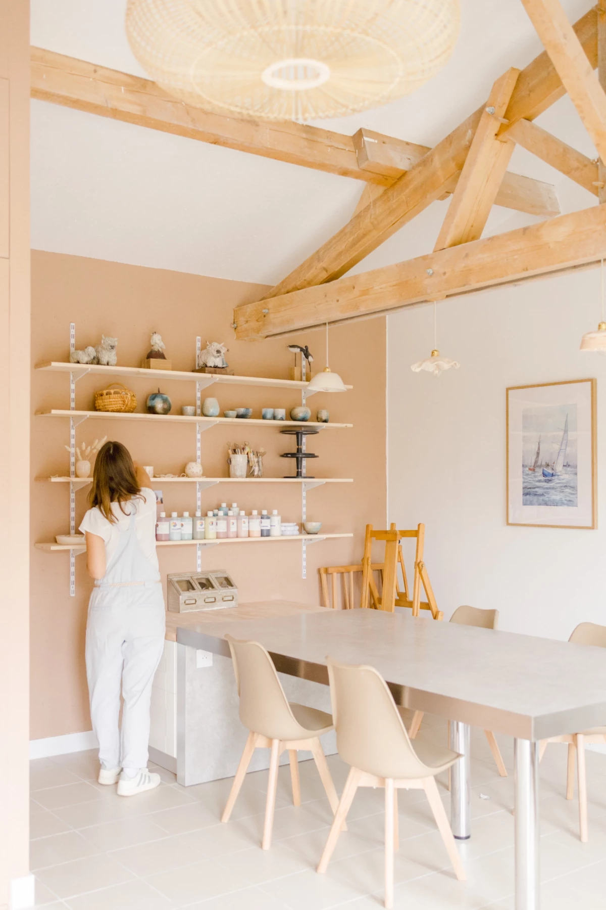 Portrait corporate d'une artisane céramiste dans son atelier lumineux aux tons beige et blanc, ambiance professionnelle et authentique