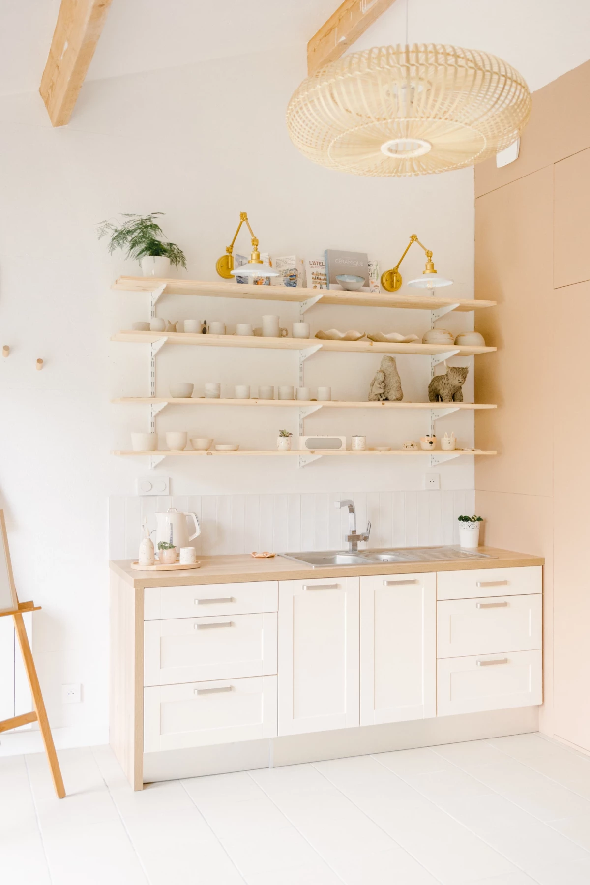 Portrait corporate dans un atelier de céramiste : espace de travail lumineux aux tons blancs et beiges avec étagères en bois