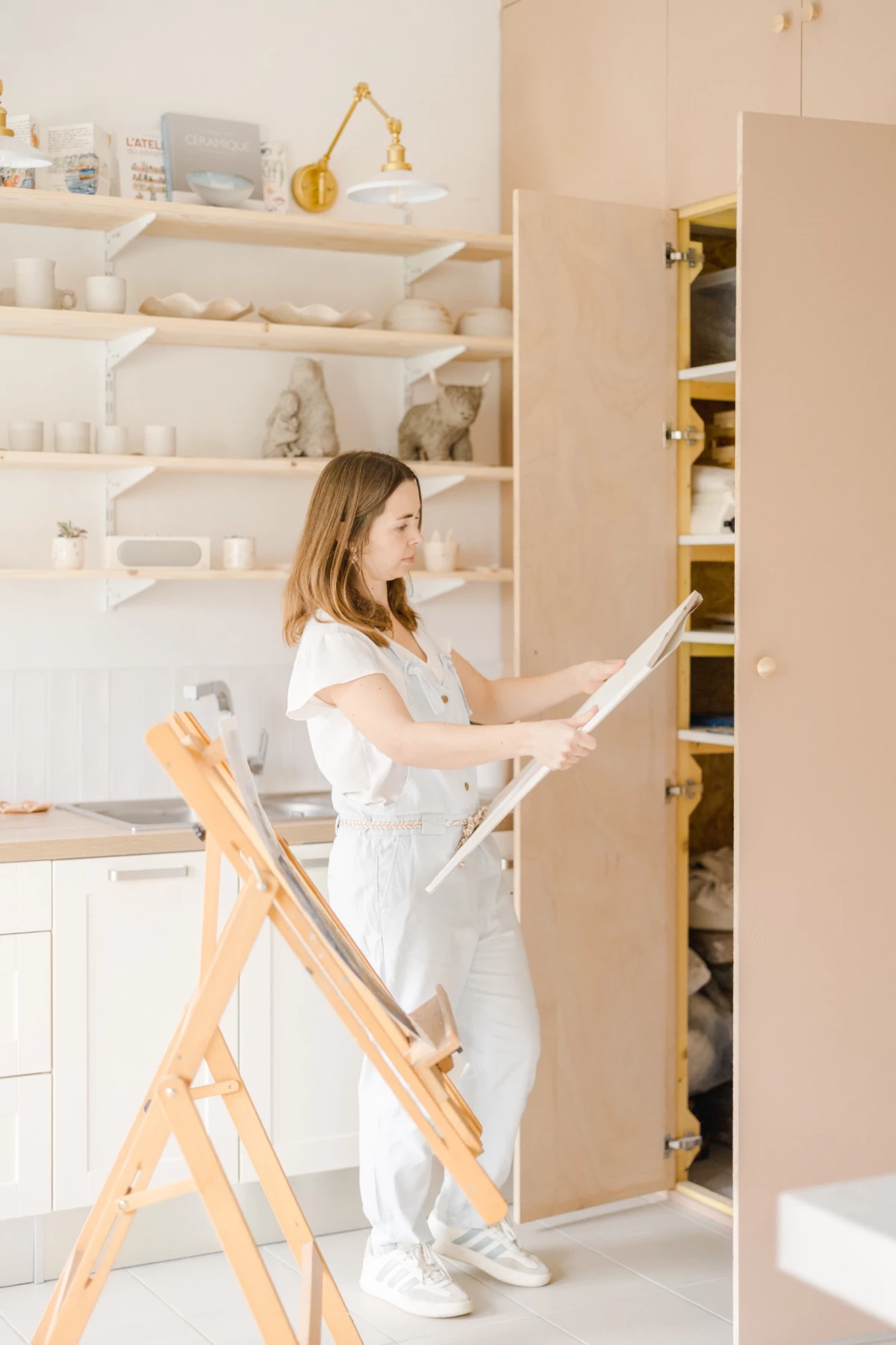 Portrait professionnel d'une céramiste aquarelliste dans son atelier lumineux, ambiance épurée et créative en Vendée