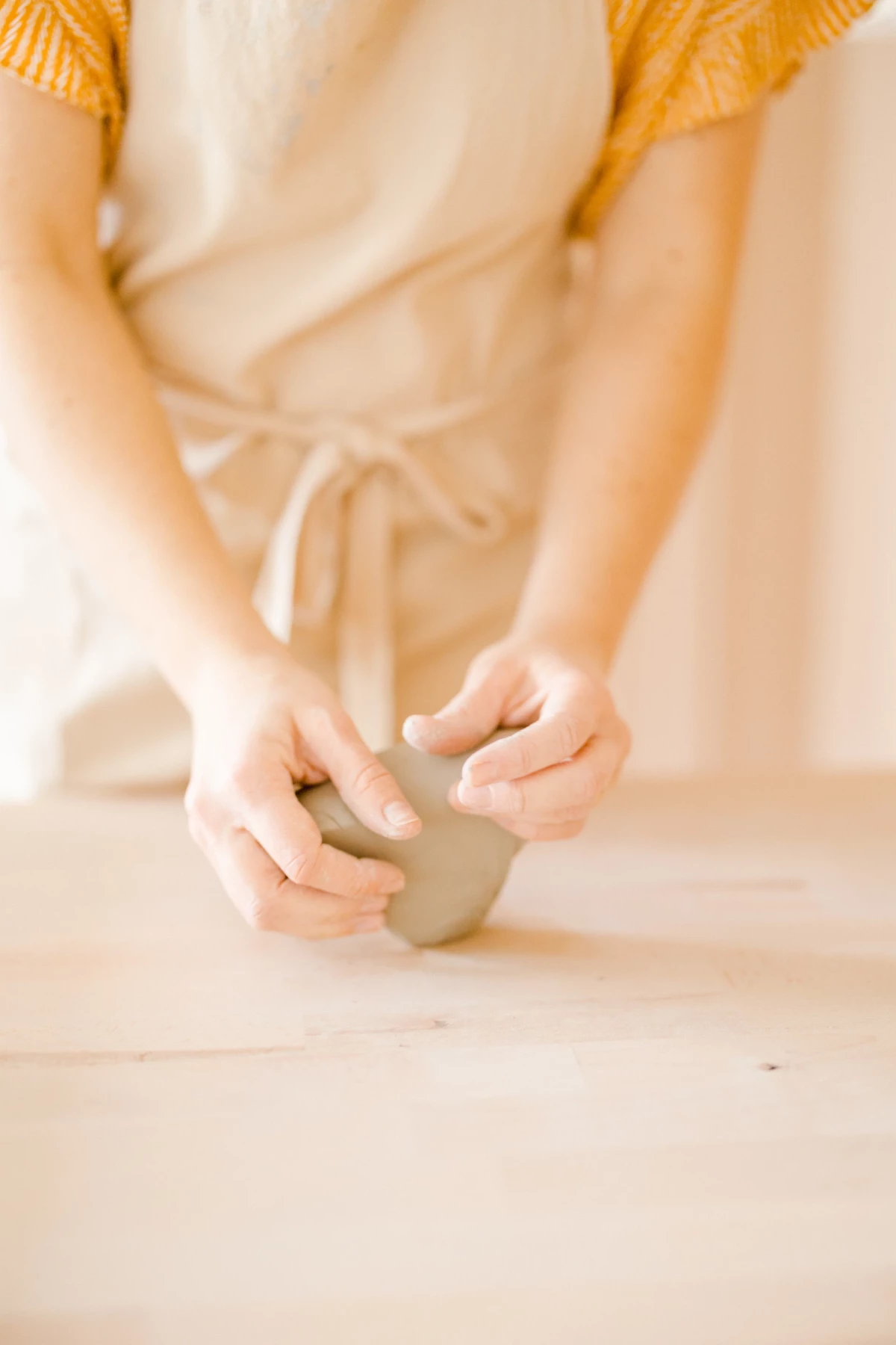 Portrait corporate d'une céramiste dans son atelier : mains travaillant l'argile avec gestes délicats, lumière douce, ambiance créative