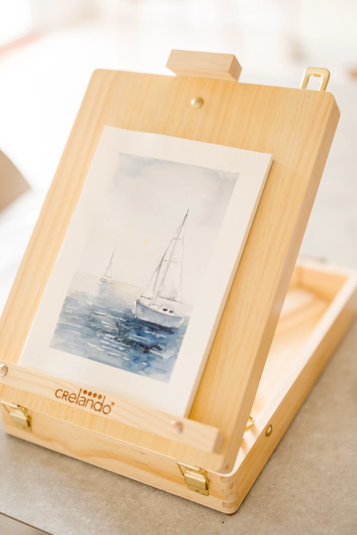 Portrait corporate dans un atelier d'aquarelle et céramique avec chevalet en bois présentant une peinture de bateau en Vendée