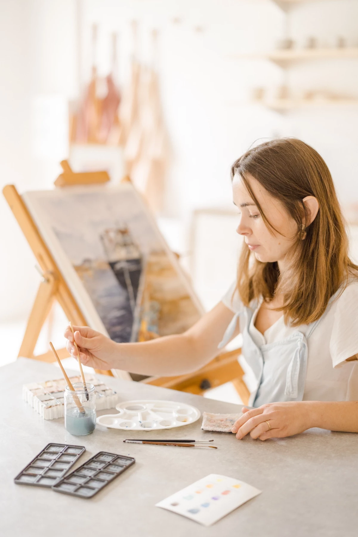 Portrait professionnel en atelier : artiste aquarelliste au travail, concentration et passion créative dans son studio lumineux