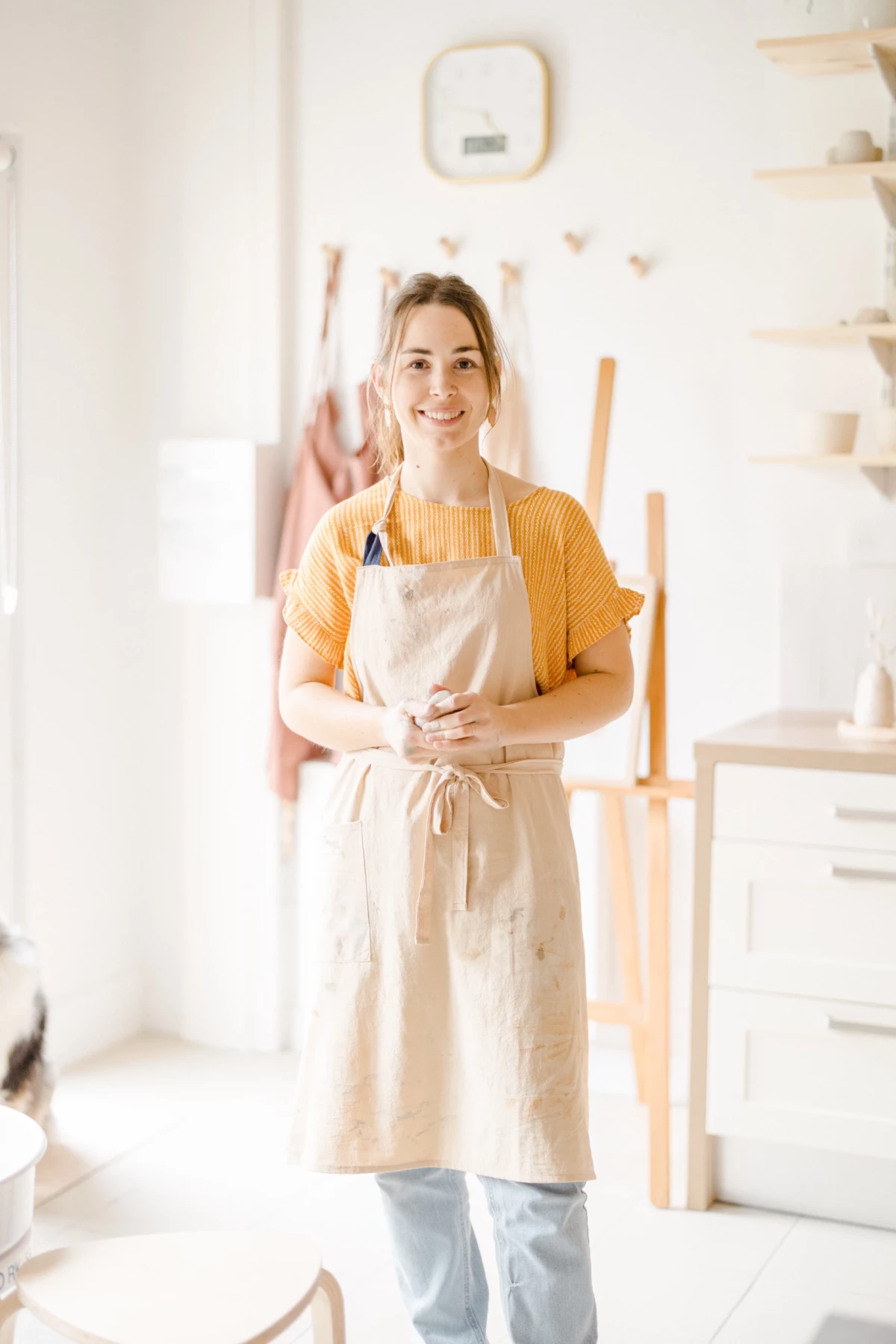 Portrait corporate en atelier : artisane céramiste souriante dans son espace de travail lumineux, ambiance chaleureuse et authentique