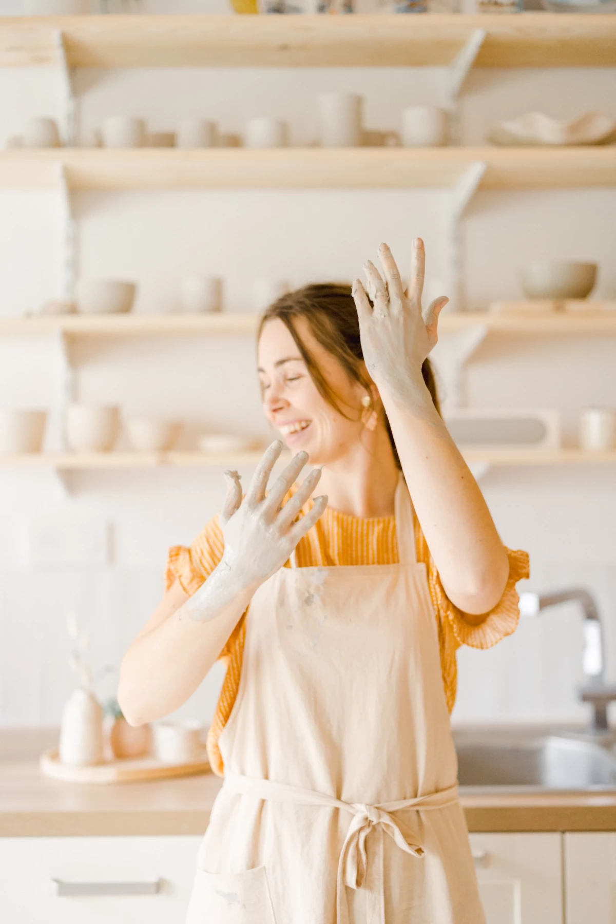 Portrait professionnel artisan céramiste dans son atelier lumineux, mains en mouvement créatif, ambiance chaleureuse et authentique