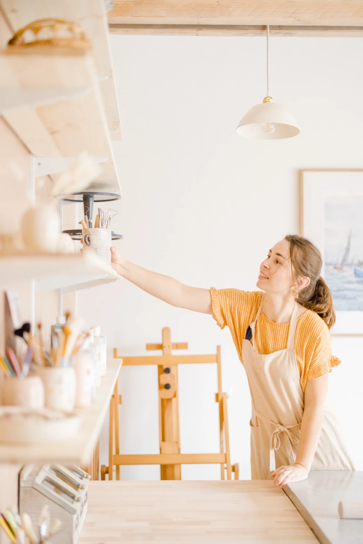 Portrait corporate en atelier : artisane céramiste dans son studio lumineux, geste créatif et sourire authentique