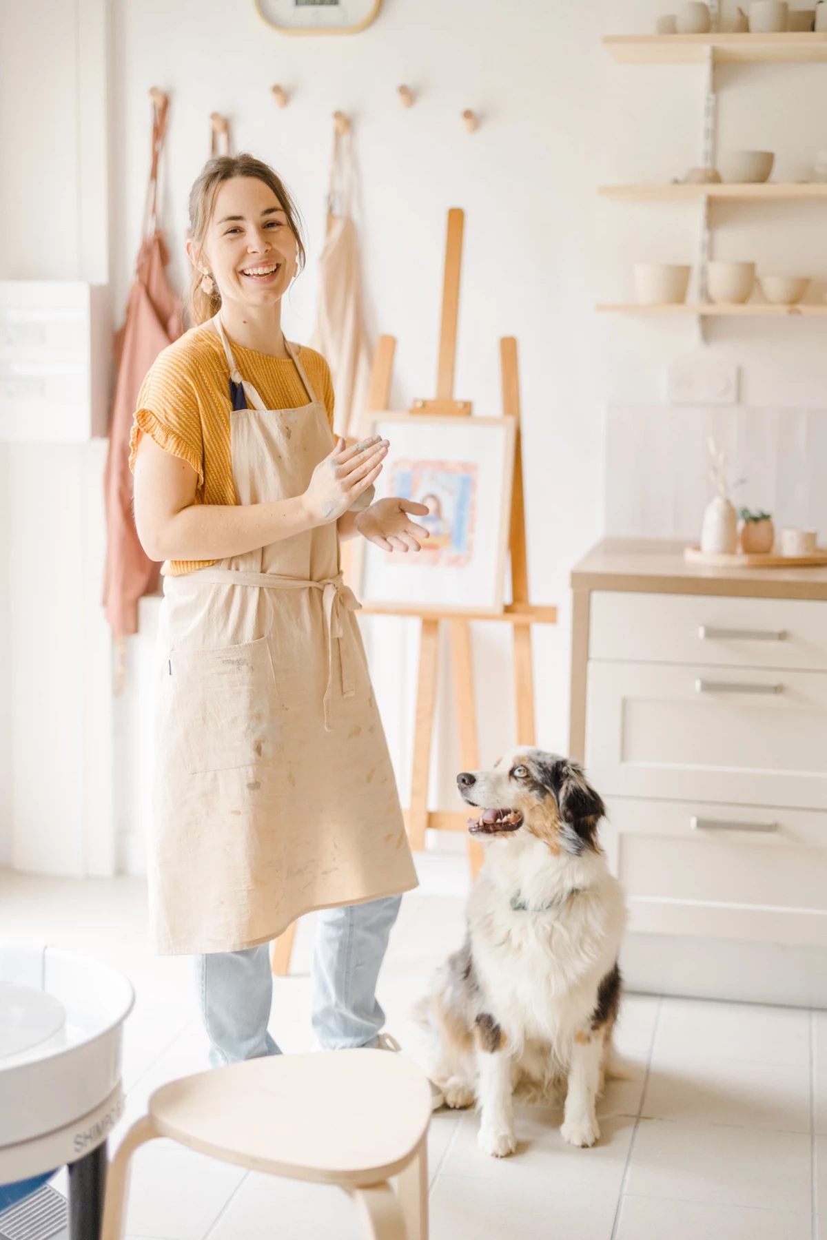 Portrait professionnel artisan céramiste dans son atelier avec son chien, sourire authentique et gestes créatifs en Vendée