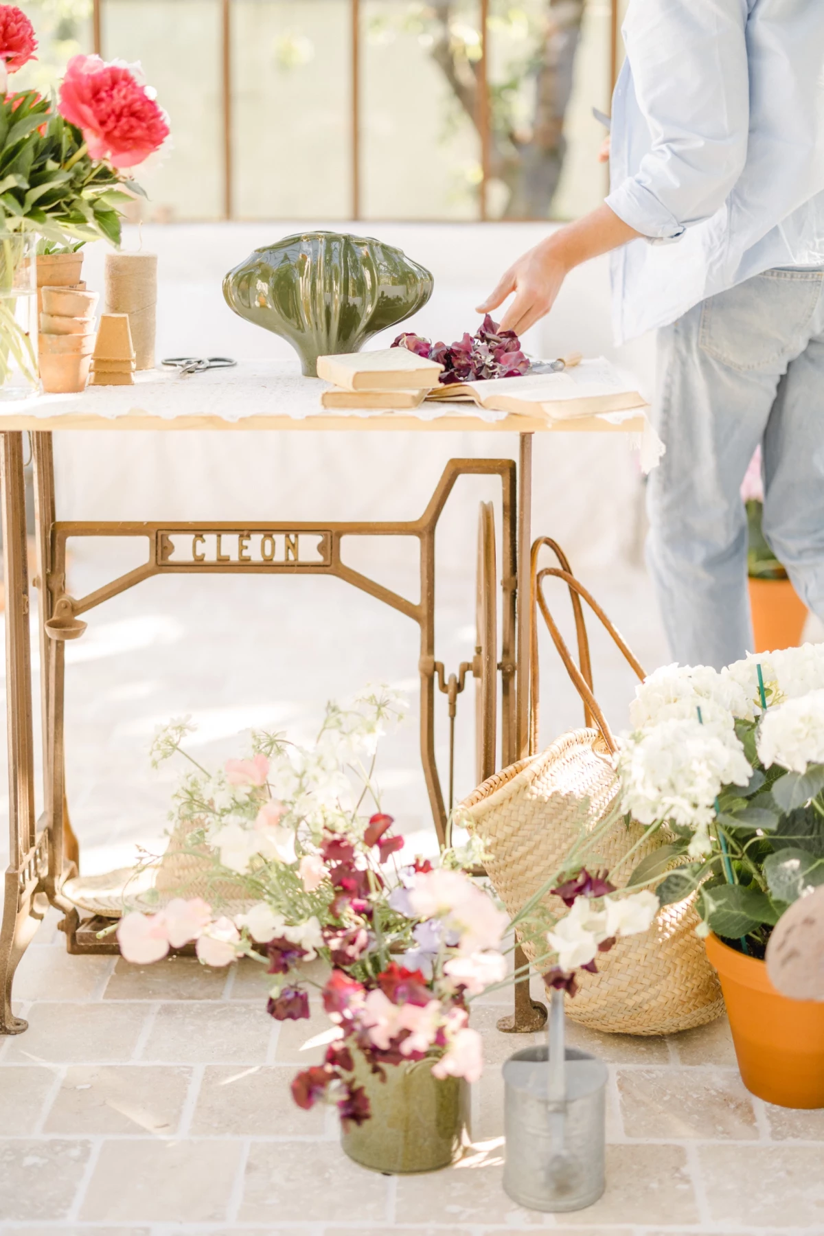Portrait corporate fleuriste : mains créant un bouquet sur table vintage, ambiance douce et lumineuse dans un atelier fleuri en Vendée