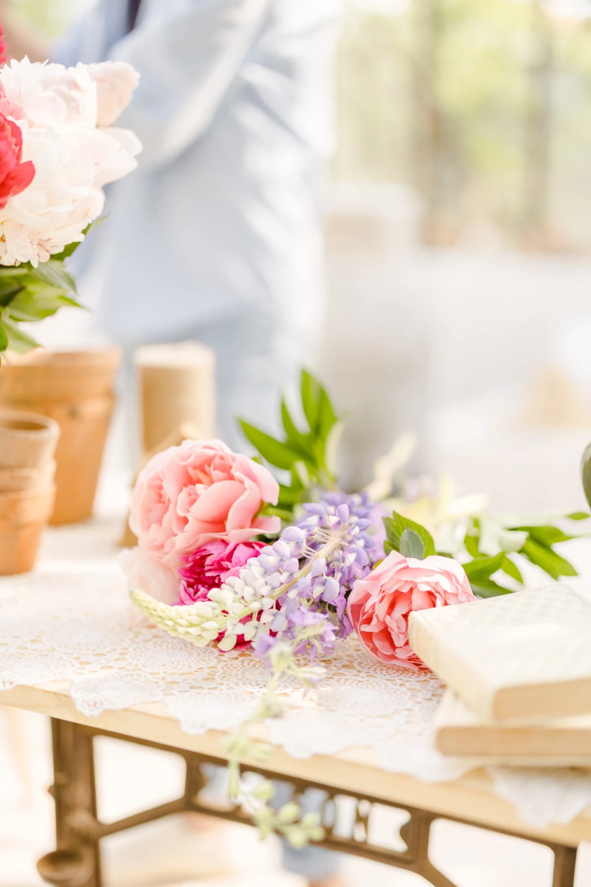 Séance corporate fleuriste : composition florale rose et blanche délicate posée sur table vintage avec verrière en arrière-plan