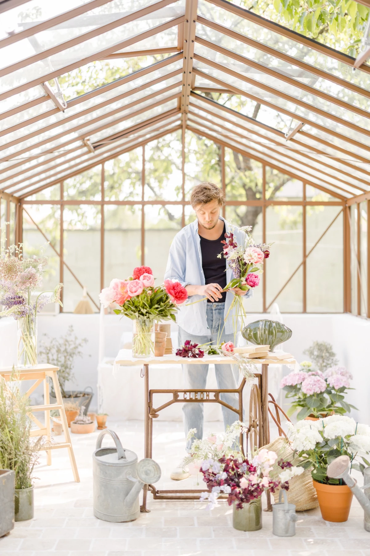 Portrait corporate fleuriste en verrière : artisan créant un bouquet de fleurs roses dans un atelier lumineux et épuré en Vendée
