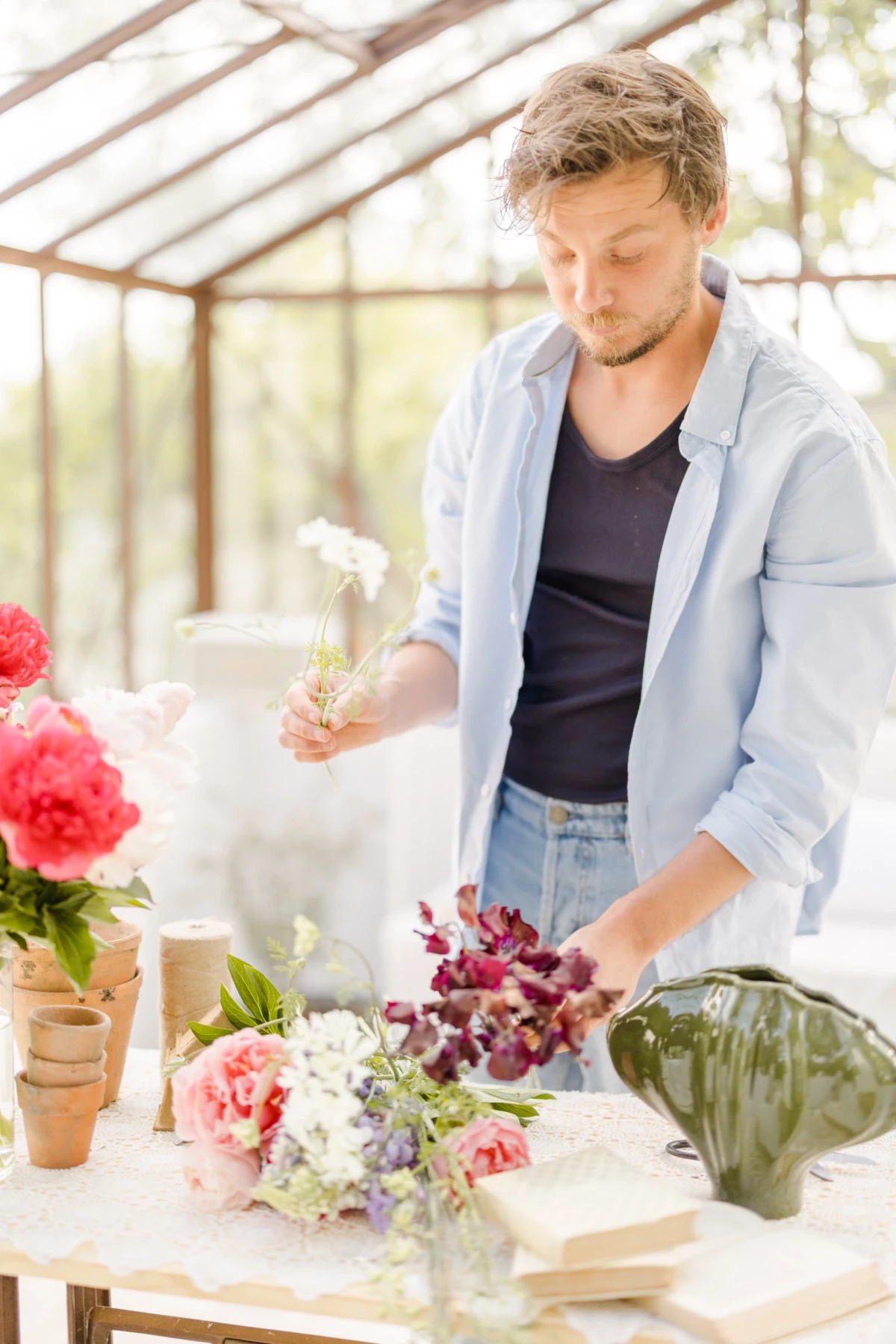 Portrait corporate fleuriste en verrière : artisan crée un bouquet de fleurs avec tendresse, ambiance lumineuse et authentique