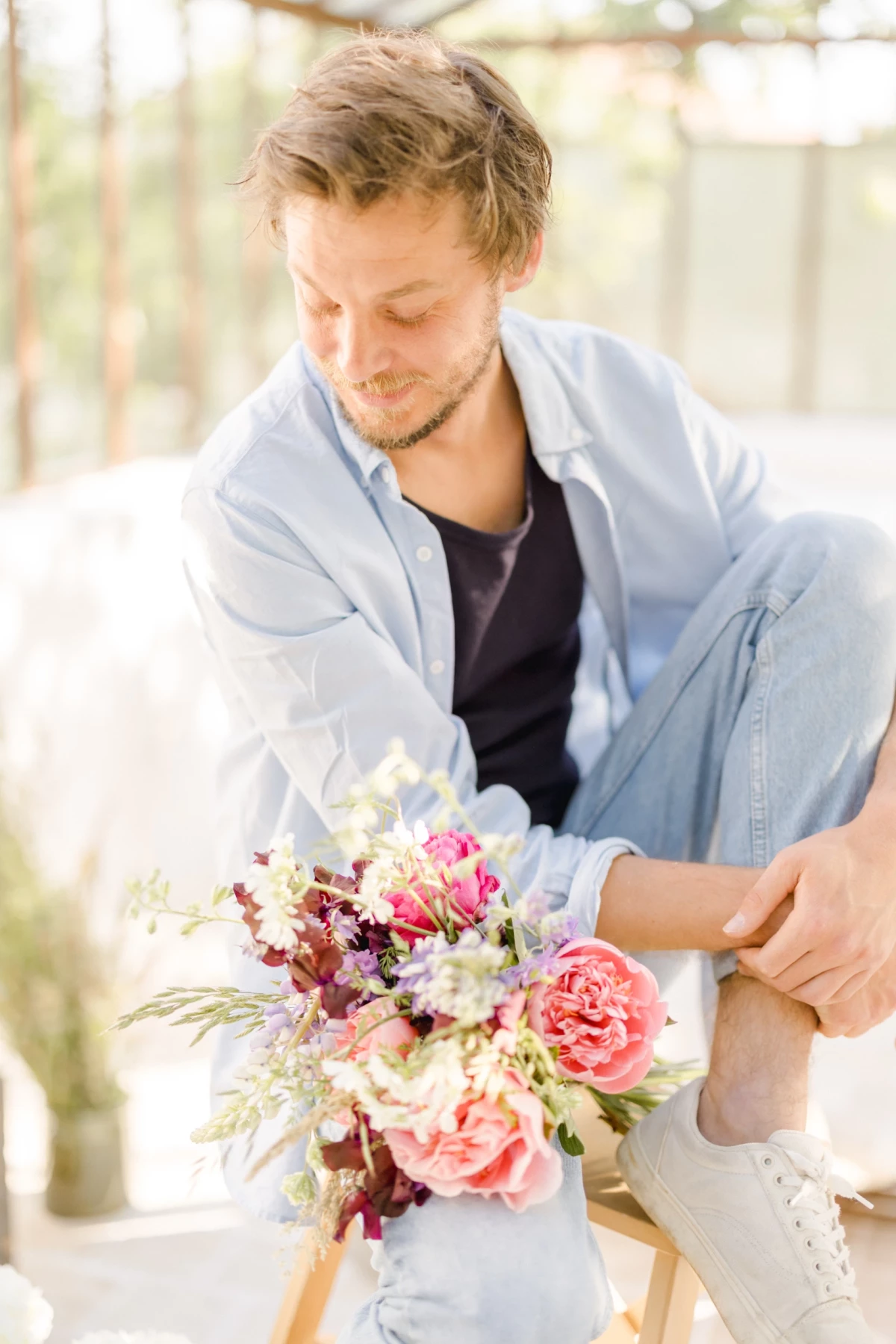 Portrait corporate fleuriste : artisan composant un bouquet de fleurs roses et blanches dans une verrière lumineuse en Vendée