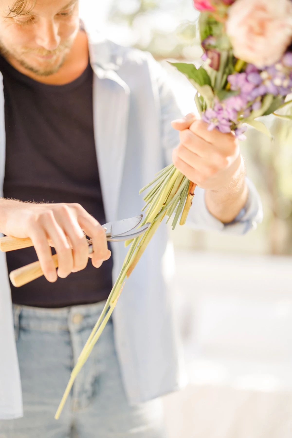 Portrait corporate fleuriste préparant un bouquet de fleurs roses et mauves, geste délicat et professionnel en atelier lumineux