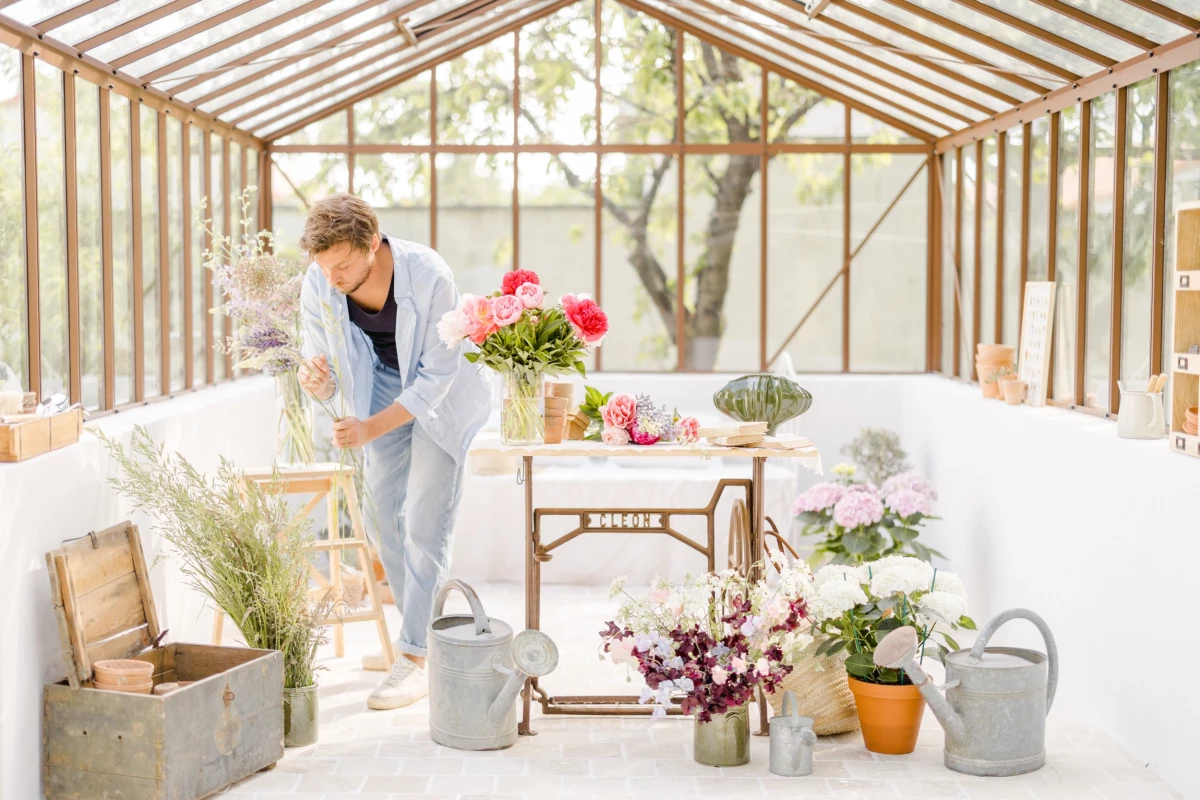 Séance corporate Vendée : fleuriste travaillant dans sa verrière lumineuse entourée de compositions florales colorées