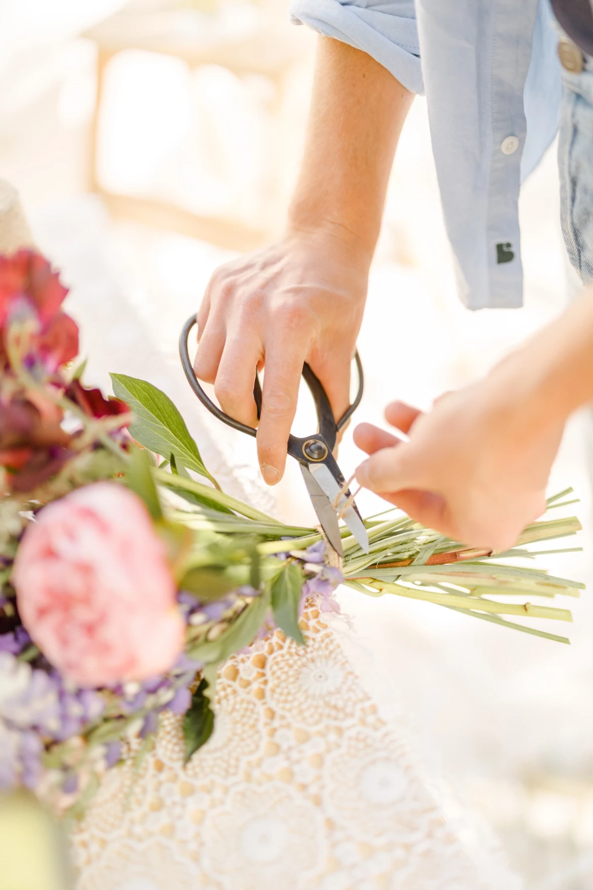 Séance corporate Vendée : fleuriste créant un bouquet artisanal, mains coupant des tiges dans un univers doux et lumineux