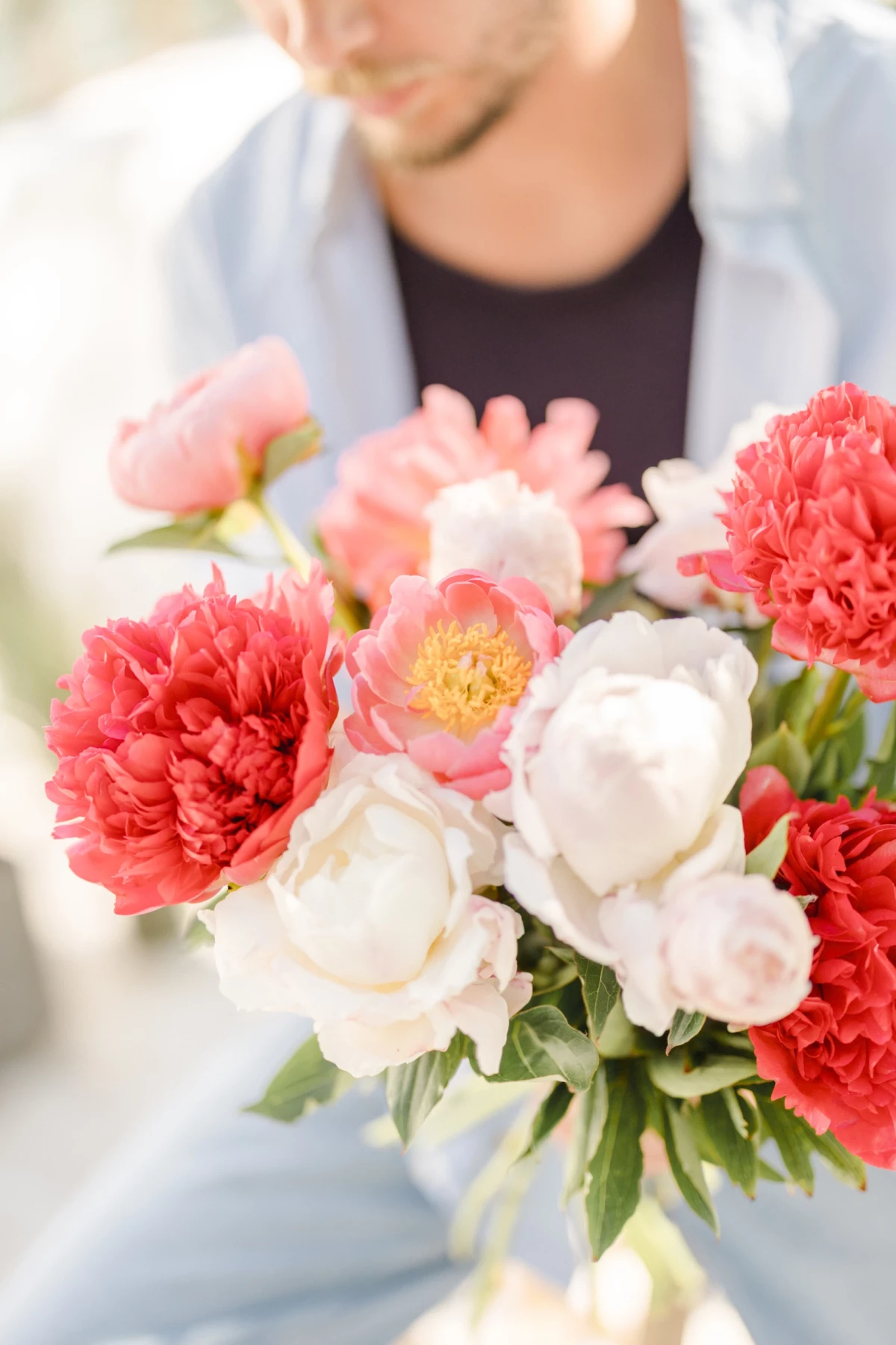 Portrait corporate fleuriste tenant un bouquet de pivoines blanches et corail, ambiance douce et lumineuse en Vendée