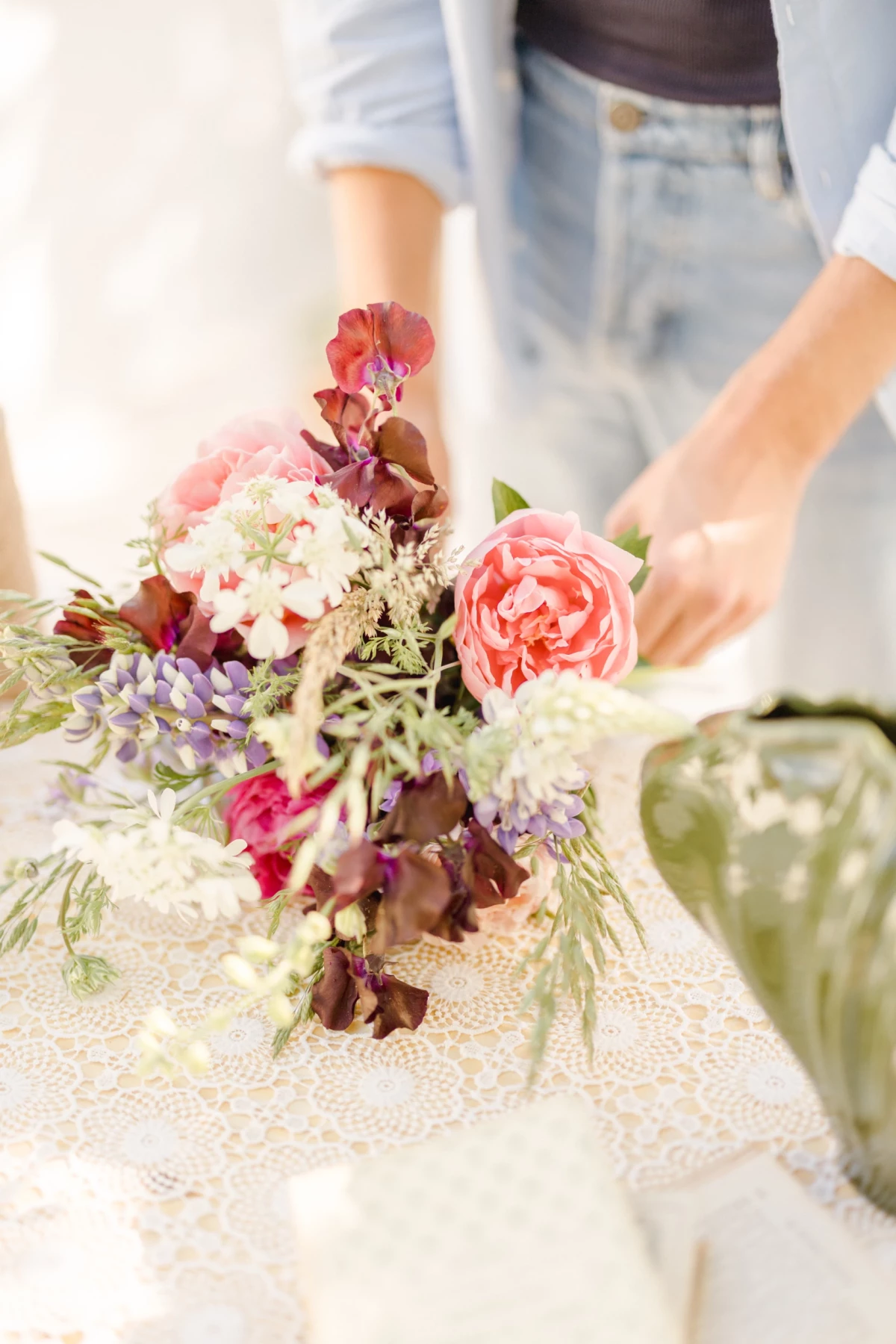 Séance corporate fleuriste : mains délicates assemblant un bouquet romantique de roses et fleurs séchées dans une verrière lumineuse