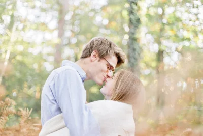 Couple complice partageant un moment tendre dans une forêt baignée de lumière automnale