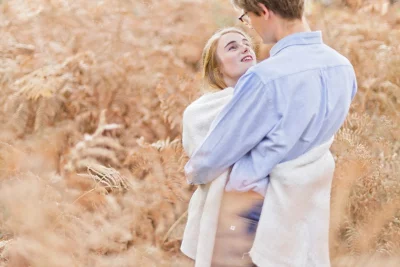 Couple enlacé dans un champ de blé doré lors d'une séance photo grossesse en extérieur