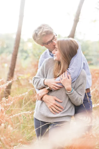 Couple enlacé en pleine nature automnale lors d'une séance grossesse, lumière douce et complice