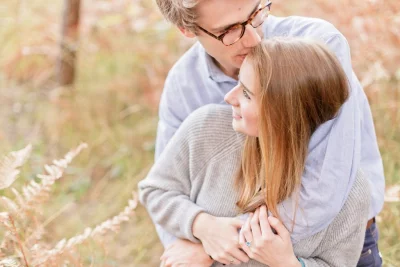 Couple enlacé dans un champ automnal, échangeant un moment de tendresse dans une lumière douce